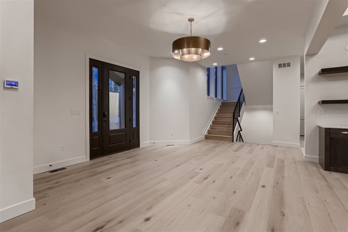 Foyer in the living room with a fancy chandelier and a brown access door in a custom home by Sheffield Homes in Evergreen, CO