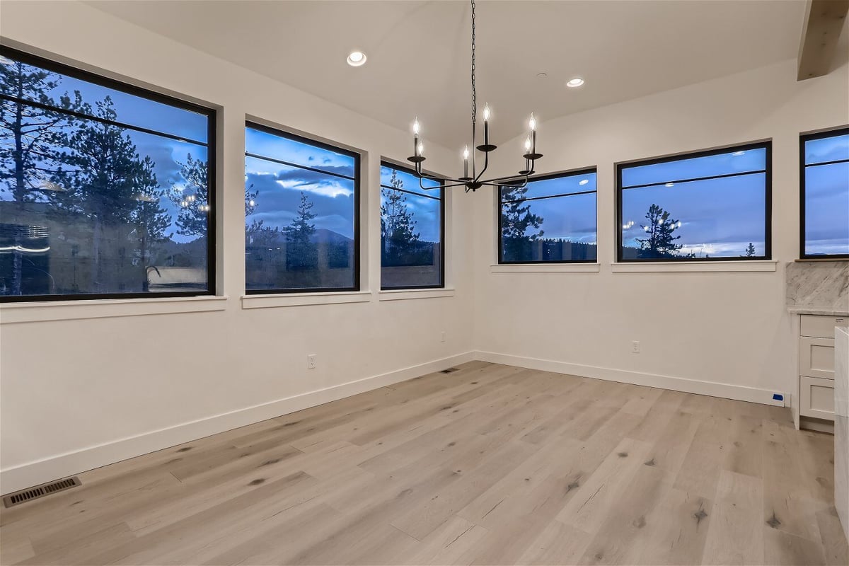 Ground-level dining room with a candle-lit chandelier and sliding windows in a house by Sheffield Homes in Evergreen, CO