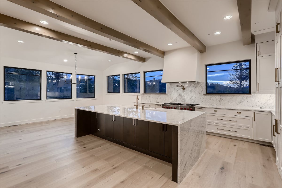 Modern kitchen featuring an island with a sleek top and wooden cabinetry base in a house by Sheffield Homes in Evergreen, CO