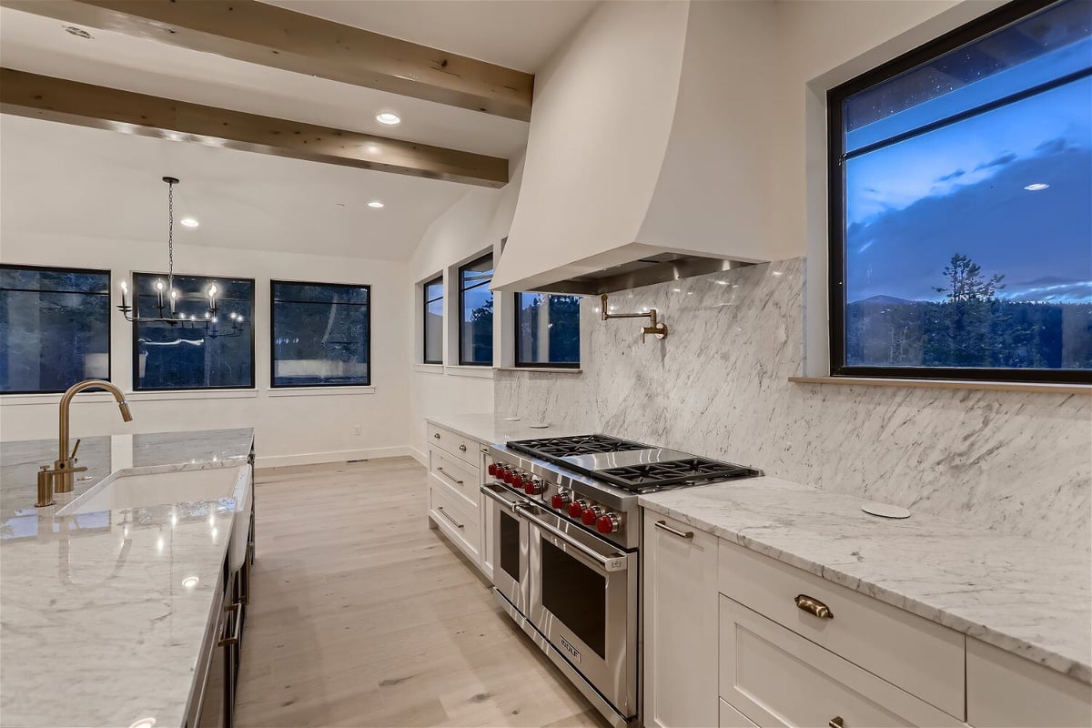 Modern kitchen with an island, stoves, and white cabinetry in a custom home by Sheffield Homes in Evergreen, CO