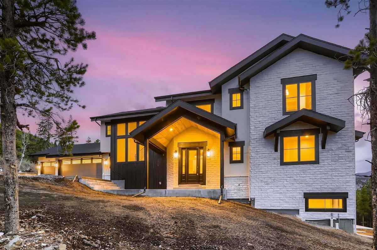 Rear exterior view of a backyard with elegant lighting outside a custom home built by Sheffield Homes in Evergreen, CO