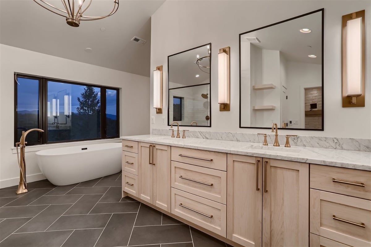 Second-floor primary bathroom featuring stylish vanities and a bathtub in a custom home by Sheffield Homes in Evergreen, CO