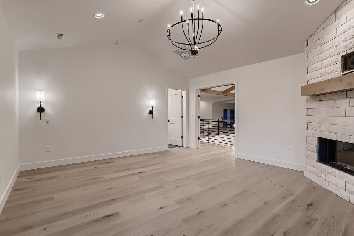 Second-floor primary bedroom with a chandelier, fireplace, and two doors in a custom home by Sheffield Homes in Evergreen, CO