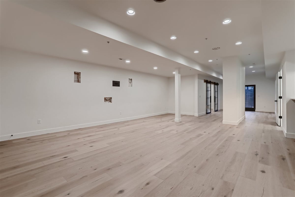 Spacious, white-themed lower-level family room in a custom home by Sheffield Homes in Evergreen, CO