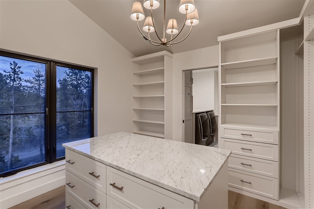 White-themed closet with detailed view inside the primary bedroom of a custom home by Sheffield Homes in Evergreen, CO