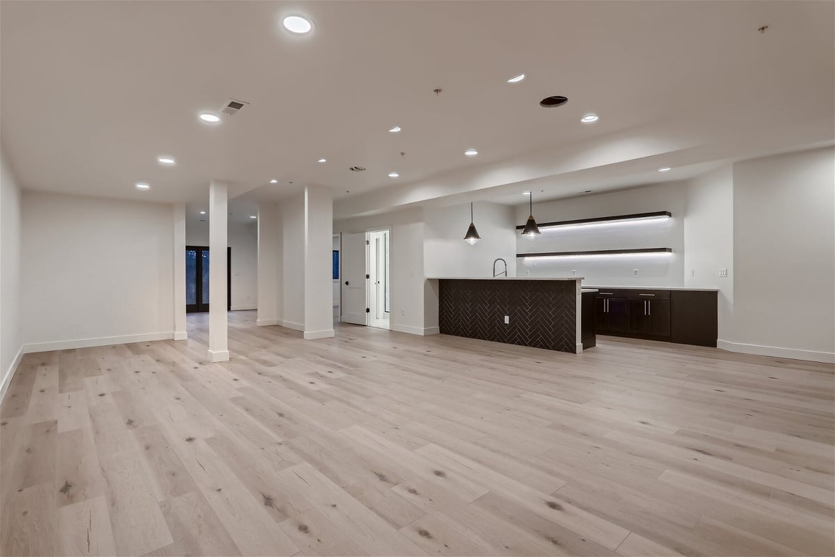 White-themed spacious lower-level family room with a bar in a custom home by Sheffield Homes in Evergreen, CO