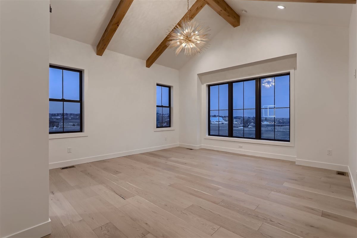 Bedroom with sliding windows, wooden ceiling craft, and a sparkling chandelier in a home by Sheffield Homes in Franktown, CO