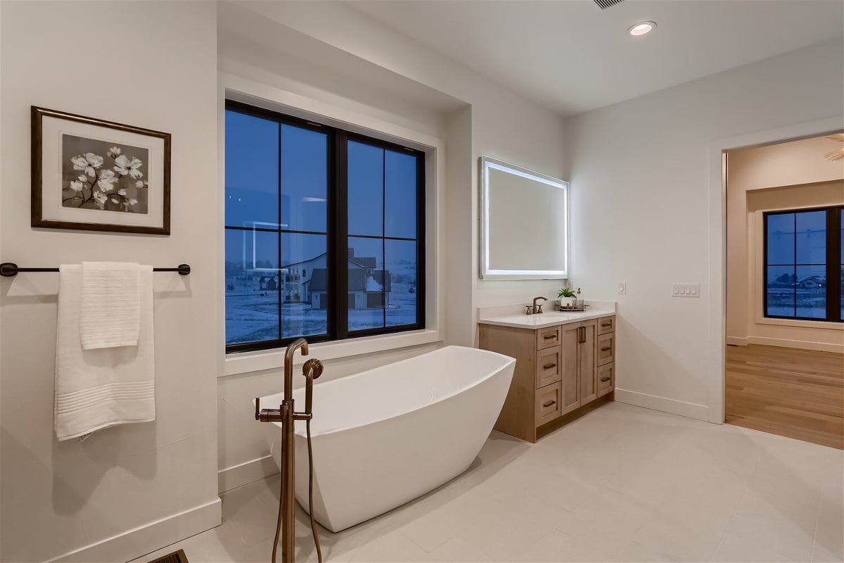 Freestanding bathtub and a wooden corner vanity in a custom home bathroom by Sheffield Homes in Franktown, CO