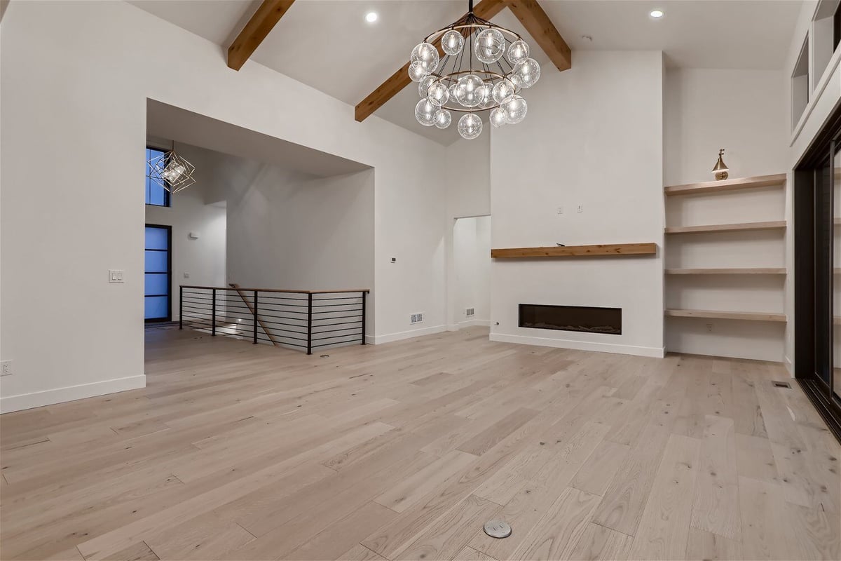 Living room featuring a fancy chandelier, a fireplace, and a foyer in a custom home by Sheffield Homes in Franktown, CO