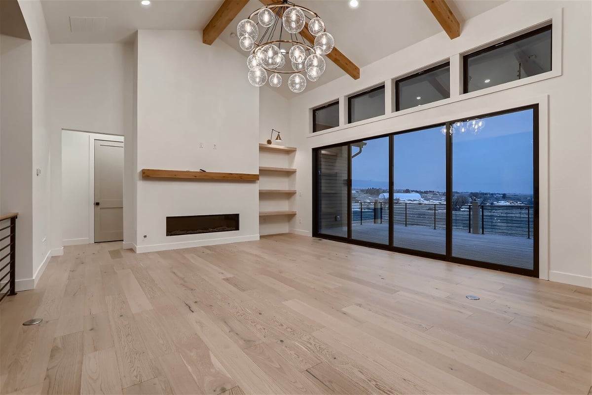 Living room featuring a fancy chandelier, large sliding doors, and a fireplace in a home by Sheffield Homes in Franktown, CO