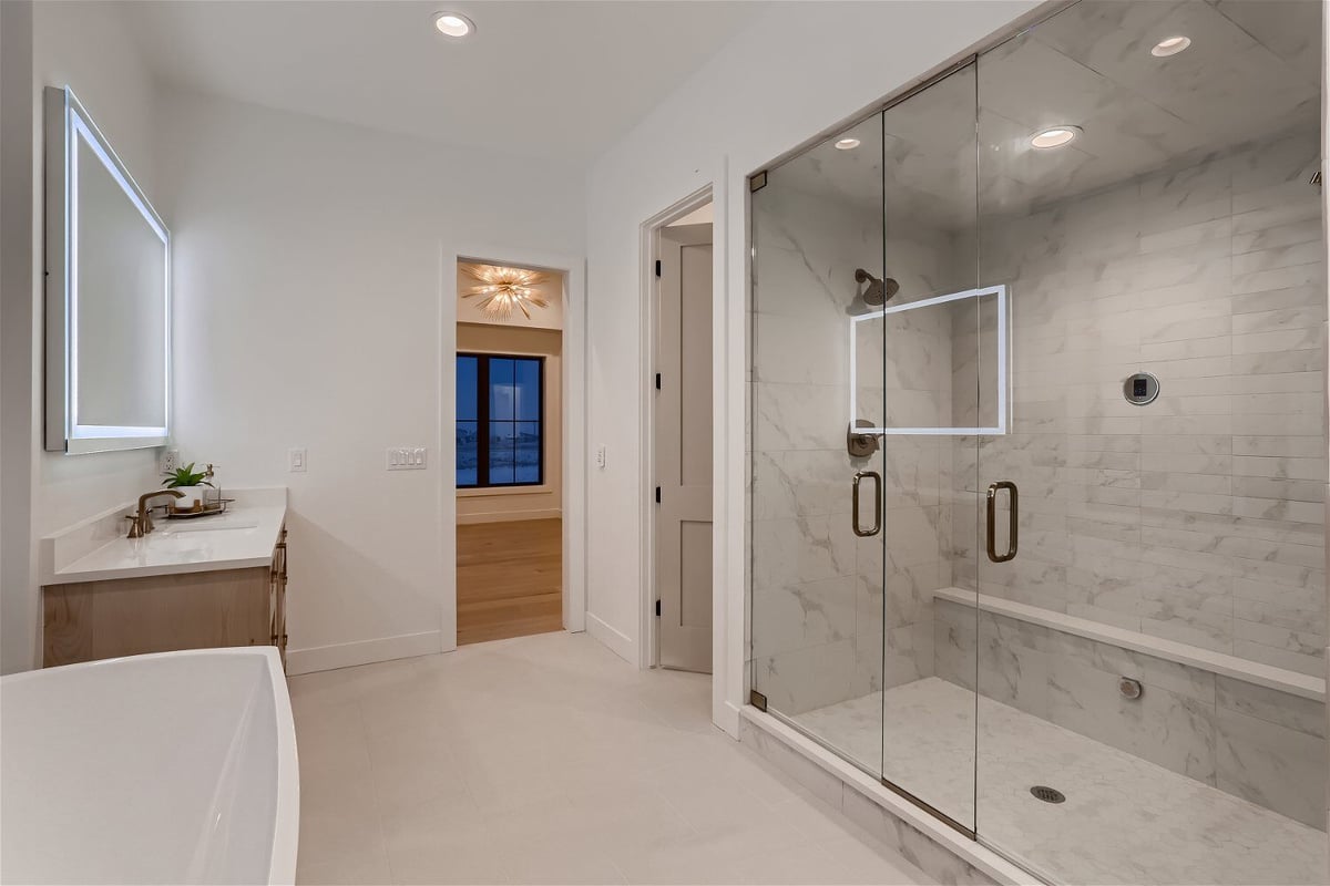 Modern shower enclosure next to a vanity in the primary bathroom of a custom home by Sheffield Homes in Franktown, CO
