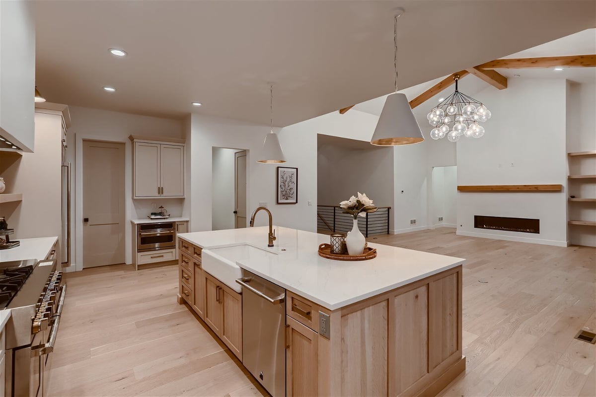 Natural wood kitchen island with a sleek top inside an open kitchen in a custom home by Sheffield Homes in Franktown, CO