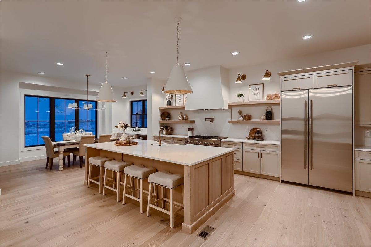Open kitchen featuring wooden cabinetry and modern appliances in a custom home by Sheffield Homes in Franktown, CO