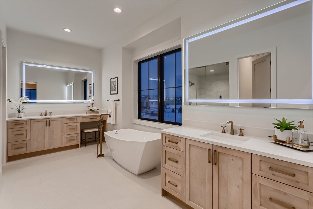 Primary bathroom with dual vanities, freestanding bathtub, and a window in a custom home by Sheffield Homes in Franktown, CO