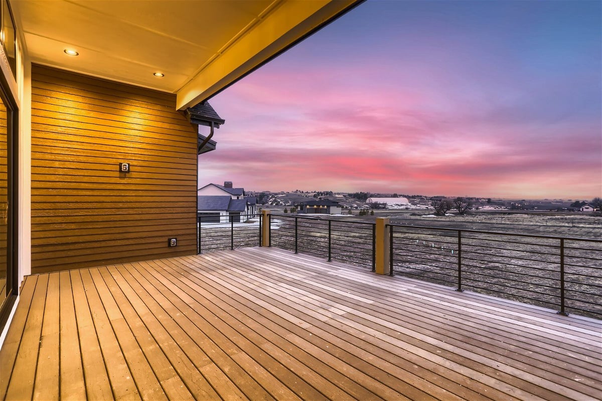 Private balcony with elegant lighting, metal fence, and expansive views from a custom home by Sheffield Homes in Franktown, CO