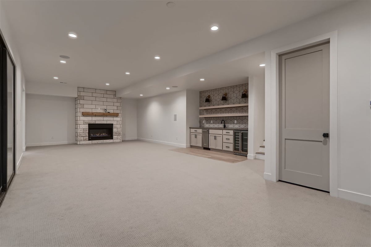 Spacious family room with carpet flooring, a wet bar, and a fireplace in a custom home by Sheffield Homes in Franktown, CO