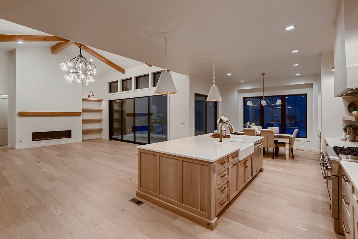 Wood island with a white sleek top and a faucet inside an open kitchen of a custom home by Sheffield Homes in Franktown, CO