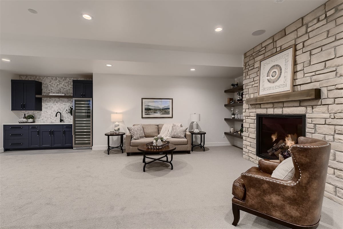 Basement with carpet flooring and a sitting area next to a fireplace in a custom home by Sheffield Homes in Franktown, CO