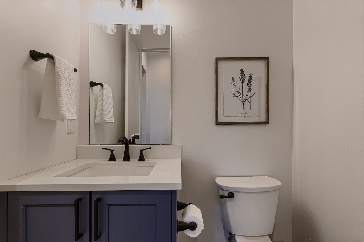 Bathroom sink with black faucet next to toilet, with towels and tissues, in a custom home by Sheffield Homes in Franktown, CO