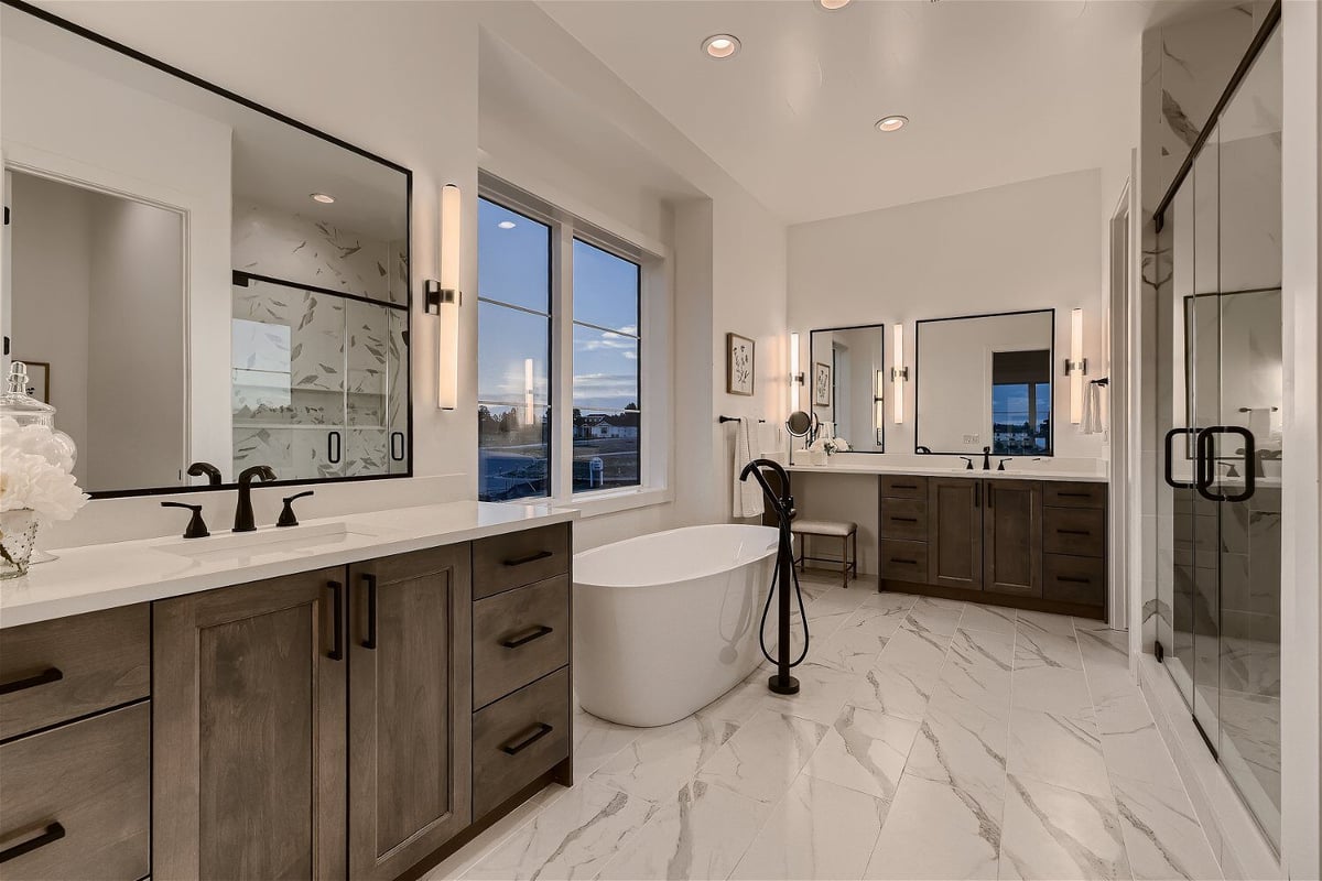 Bathroom with marble flooring, a shower area, bathtub, and dual vanities in a custom home by Sheffield Homes in Franktown, CO