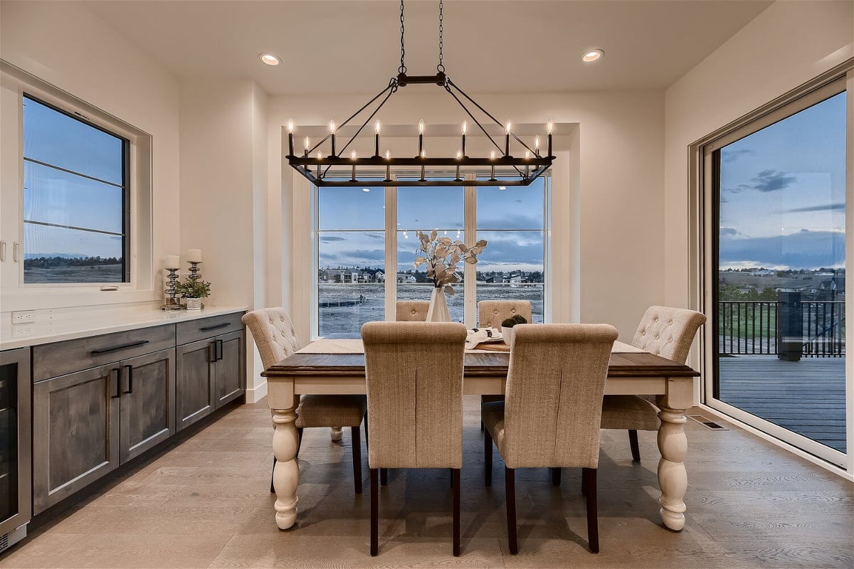 Breakfast area with dining table, fancy chandelier, and sliding windows in a custom home by Sheffield Homes in Franktown, CO