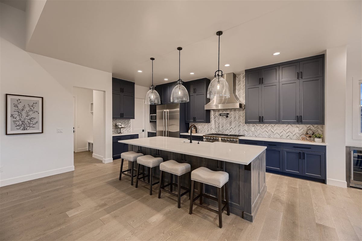 Grey and white island with three hanging lamps in an open kitchen by Sheffield Homes in Franktown, CO