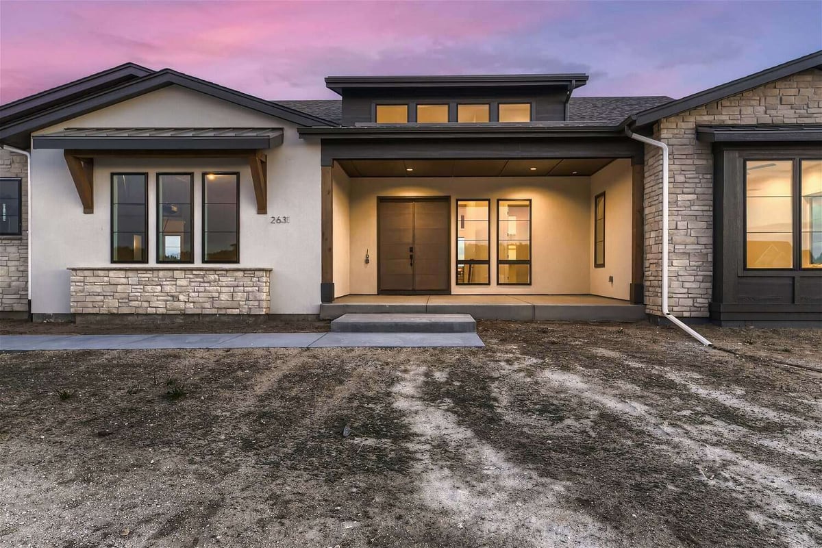 Low-angle exterior front main entrance of custom home with elegant lighting built by Sheffield Homes in Franktown, CO