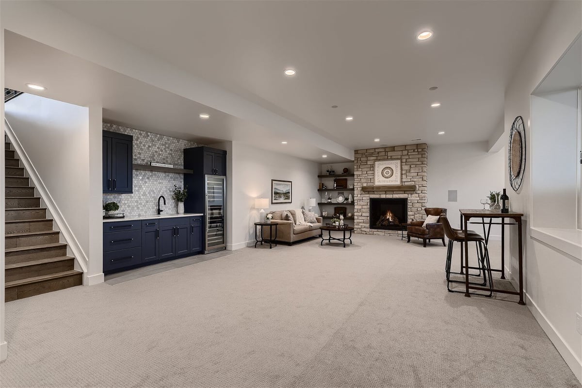 Lower level basement with landing stairs, a wetbar, and a sitting area with a fireplace - Sheffield Homes in Franktown, CO