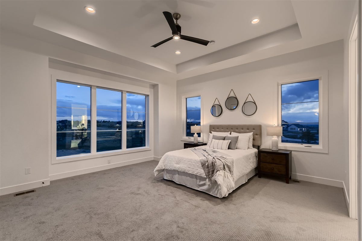 Modern primary bedroom with multiple sliding windows and carpet flooring in a custom home by Sheffield Homes in Franktown, CO