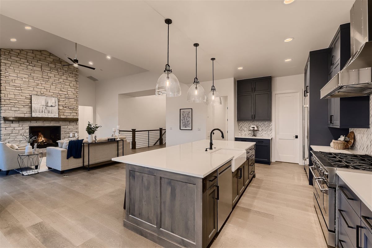 Open kitchen in a large living room with a sitting area and fireplace in a custom home by Sheffield Homes in Franktown, CO