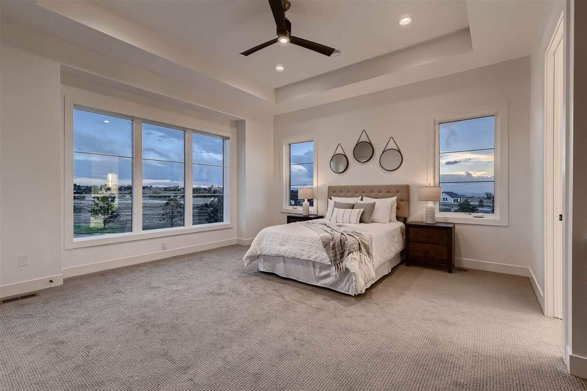 Primary bedroom with carpet flooring and sliding windows in a custom home project by Sheffield Homes in Franktown, CO