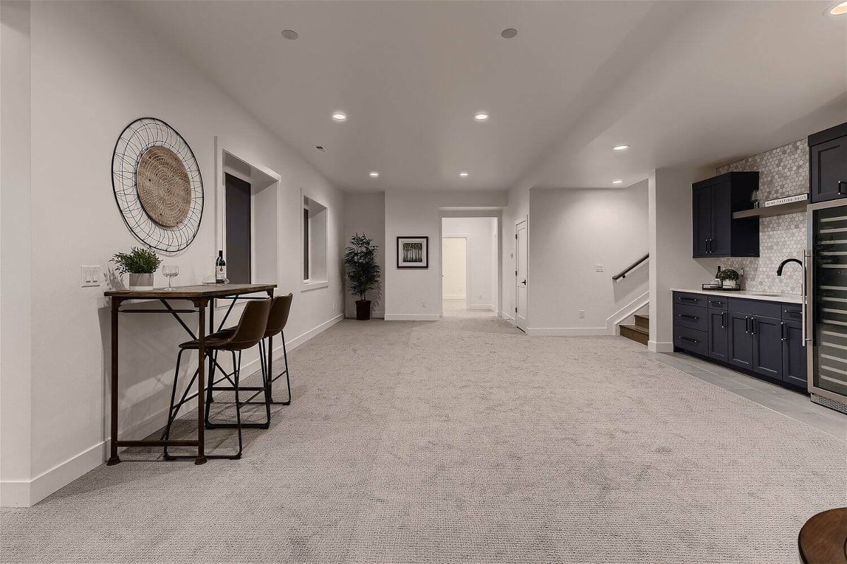 Side table and two chairs in front of a wetbar in the lower basement of a custom home by Sheffield Homes in Franktown, CO