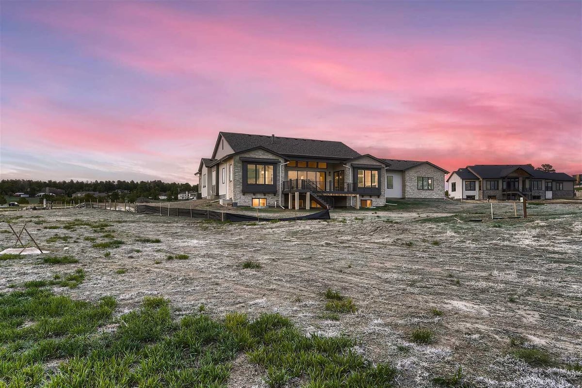 Wide-angle exterior daylight rear view of a large custom home with a backyard built by Sheffield Homes in Franktown, CO