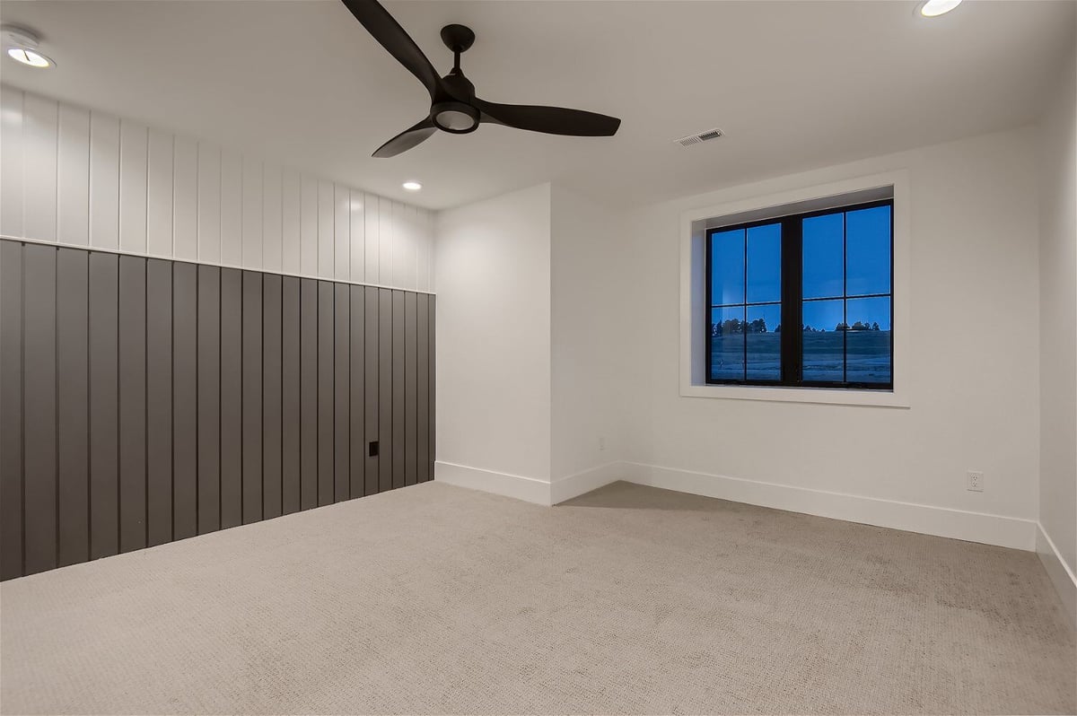 Bedroom with a custom wall design, sliding window, and ceiling fan in a custom home by Sheffield Homes in Franktown, CO