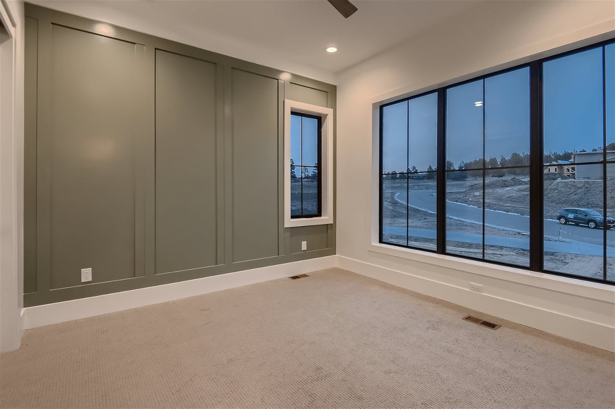 Bedroom with a green feature wall design and sliding windows in a custom home by Sheffield Homes in Franktown, CO