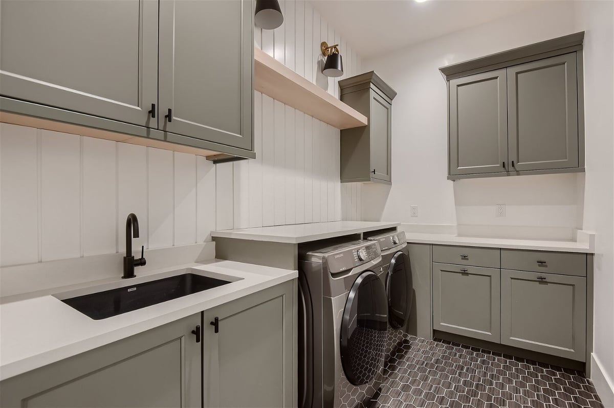Compact laundry room with a washing machine, cabinetry, and sink in a custom home by Sheffield Homes in Franktown, CO