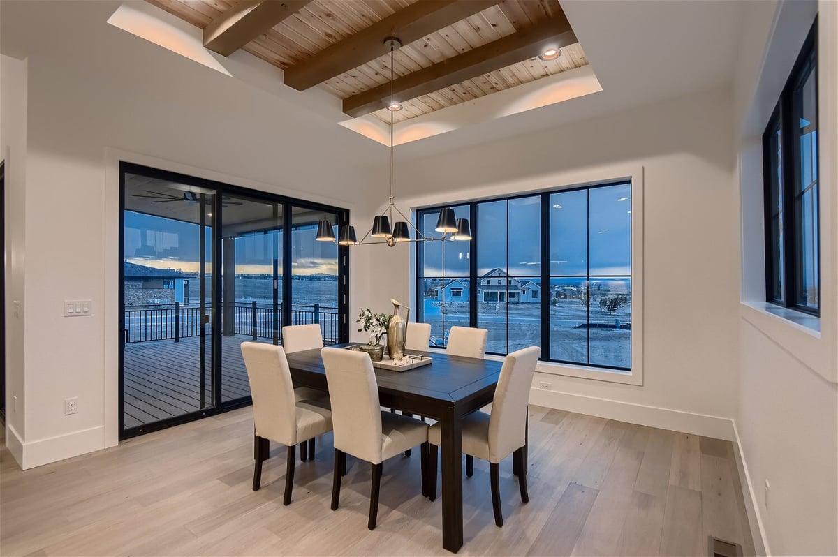 Dining room with a table and chairs under a minimalistic chandelier in a custom home by Sheffield Homes in Franktown, CO