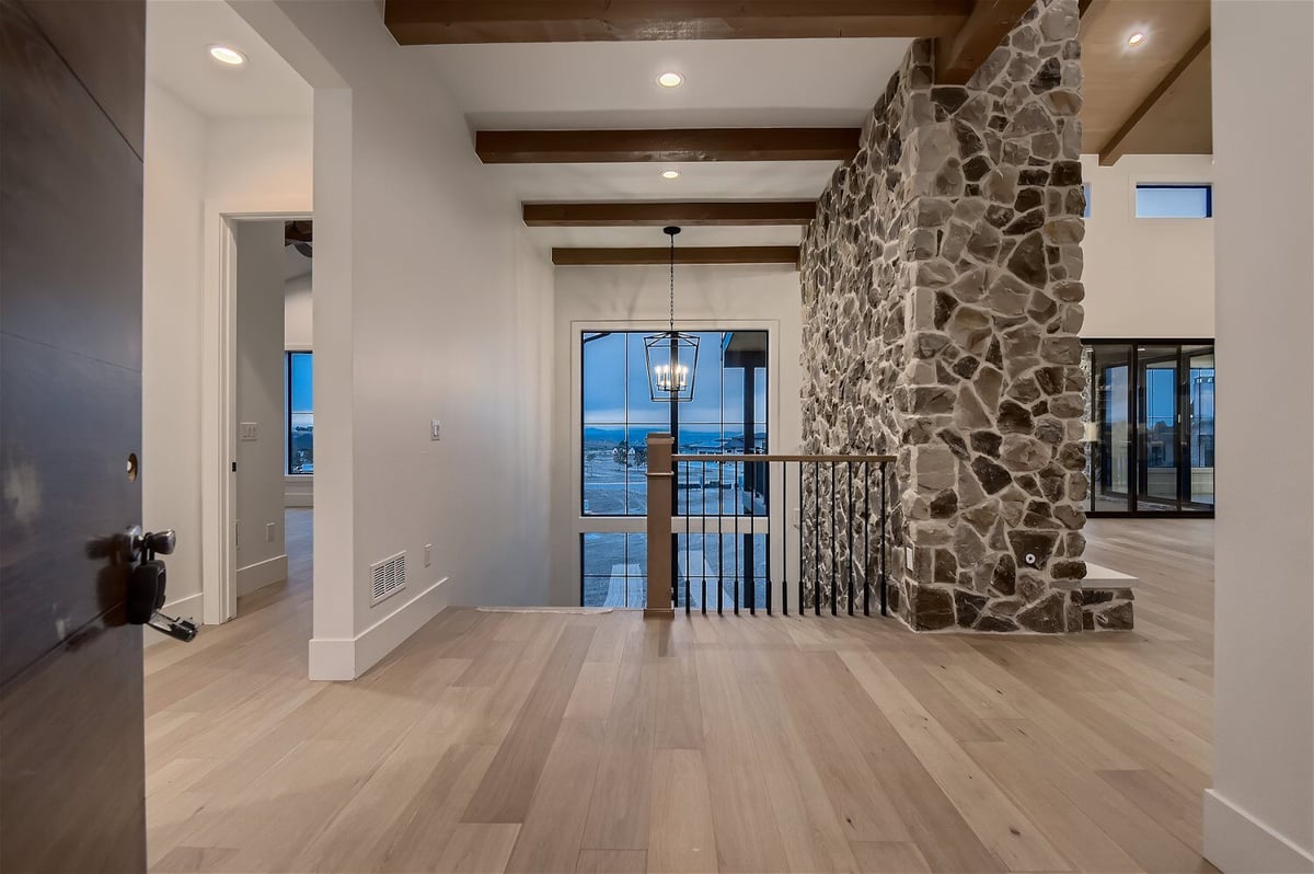 Foyer with a metal fence next to a distinctive stone accent wall design in a custom home by Sheffield Homes in Franktown, CO