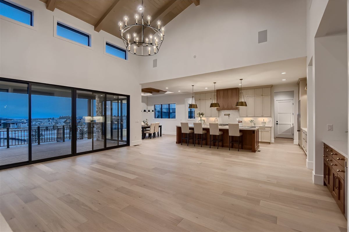 Living room with multiple sliding doors and a kitchen island with seats in a custom home by Sheffield Homes in Franktown, CO