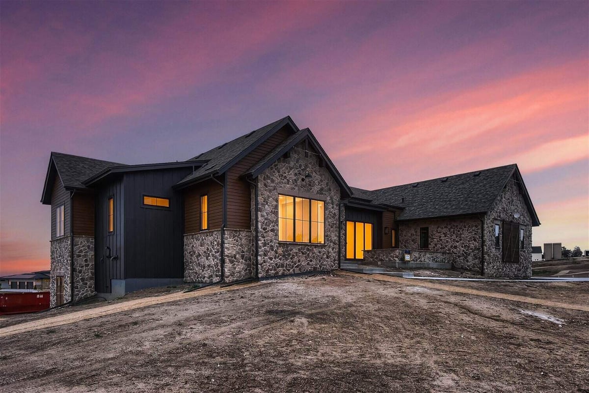 Low light exterior front view of a custom home with a front yard by Sheffield Homes in Franktown, CO