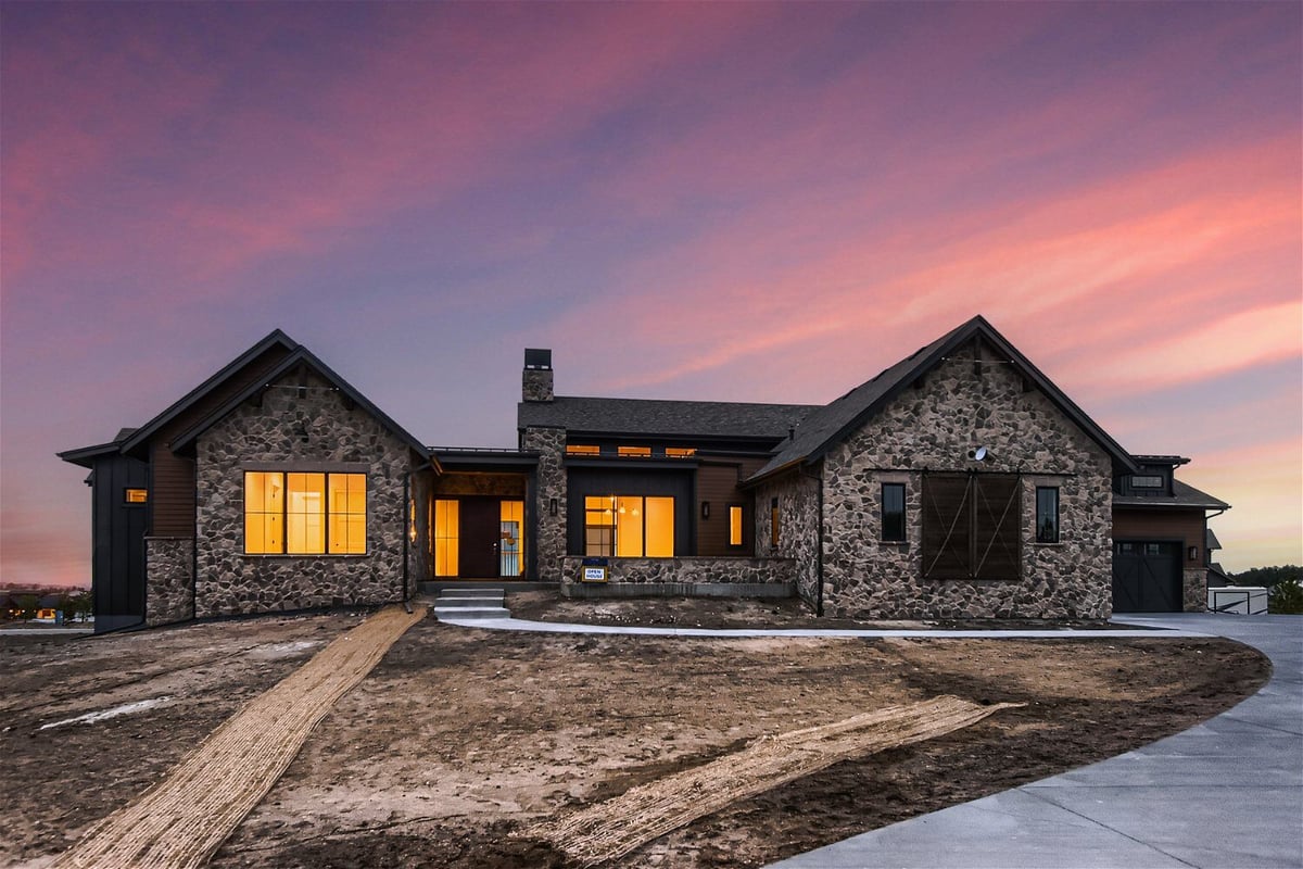 Low light exterior front view of a custom home with stone accent wall designs by Sheffield Homes in Franktown, CO