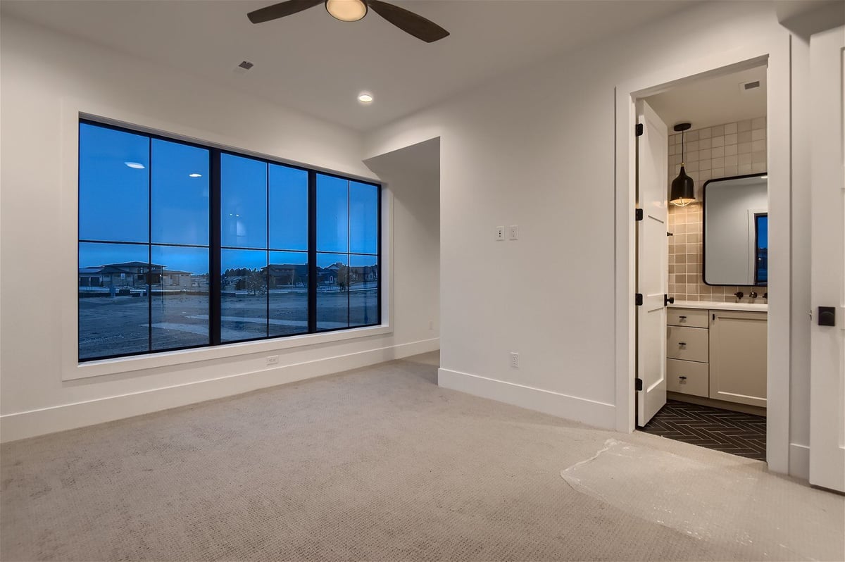 Lower-level bedroom with sliding windows and an attached restroom in a custom home by Sheffield Homes in Franktown, CO