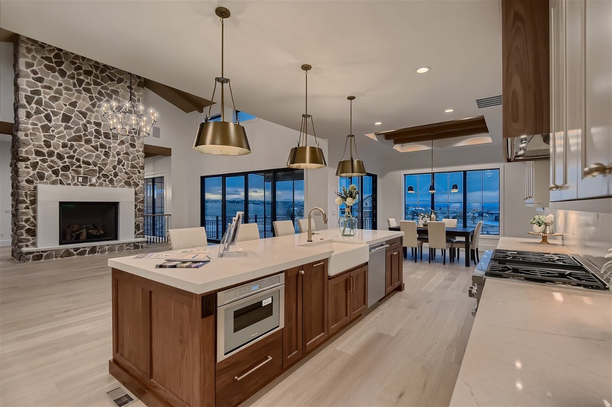 Modern open kitchen island with a natural wood base and sleek white top in a living room by Sheffield Homes in Franktown, CO