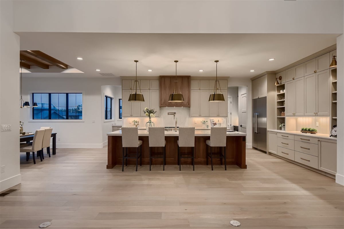 Modern open kitchen with an island and seating, and white cabinetry in a custom home by Sheffield Homes in Franktown, CO