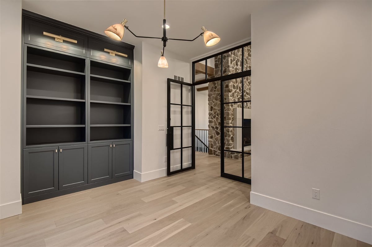 Office room with a book closet, entry door, and chandelier in a custom home by Sheffield Homes in Franktown, CO