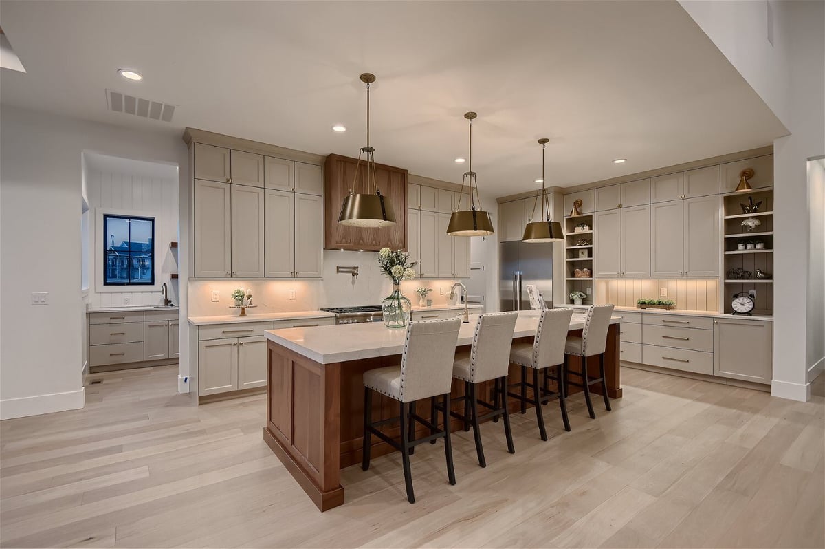 Open kitchen with an island and seating, and hanging lamp fixtures in a custom home by Sheffield Homes in Franktown, CO