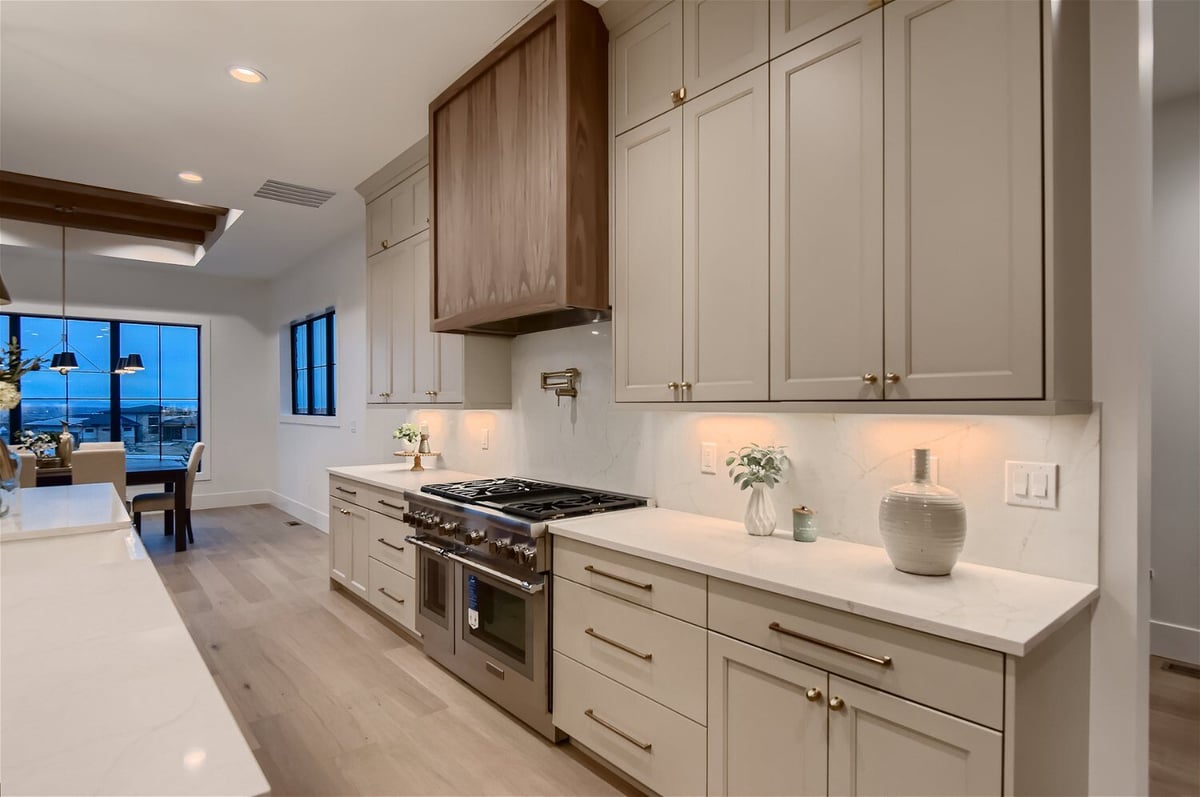 Open kitchen with sleek white cabinets and a stainless steel stove in a custom home by Sheffield Homes in Franktown, CO
