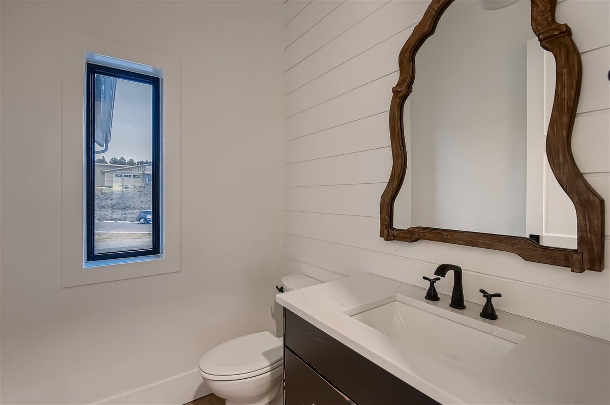Powder room with a unique mirror design, a toilet, and a small window in a custom home by Sheffield Homes in Franktown, CO