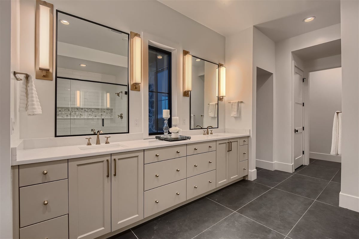 Premium primary bathroom with grey marble flooring and dual vanities in a custom home by Sheffield Homes in Franktown, CO