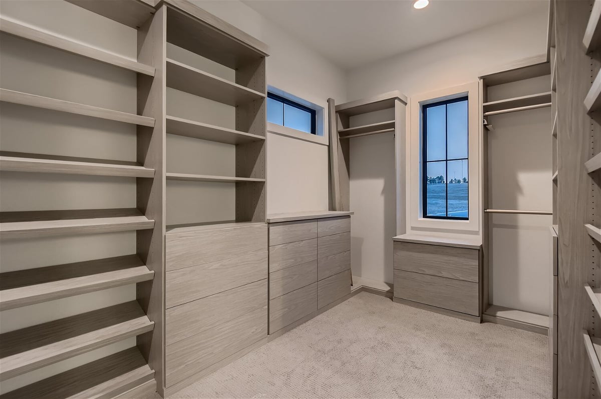 Spacious closet with a grayish-white color theme and multiple sections in a custom home by Sheffield Homes in Franktown, CO